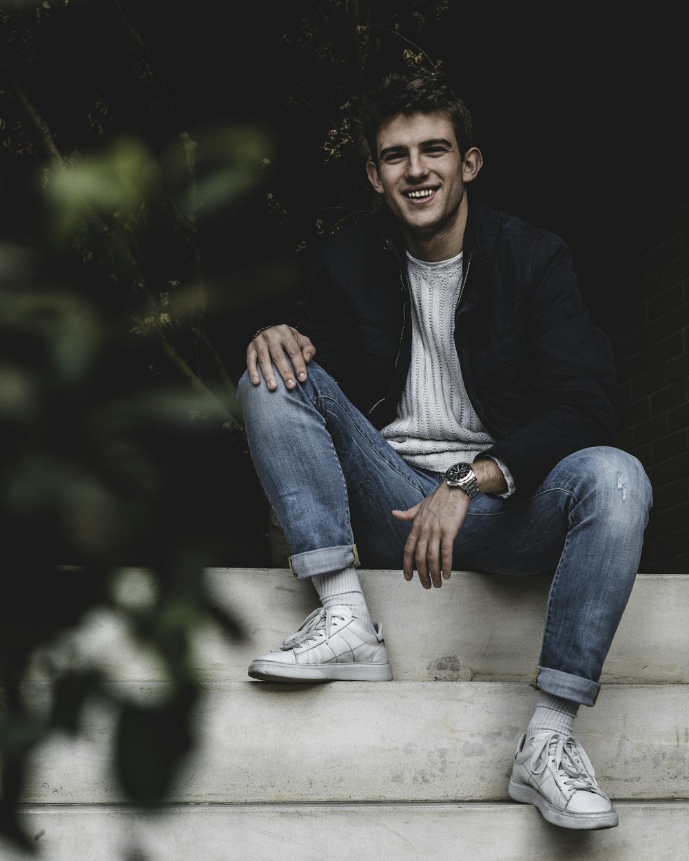 man in black jacket sitting on white concrete bench