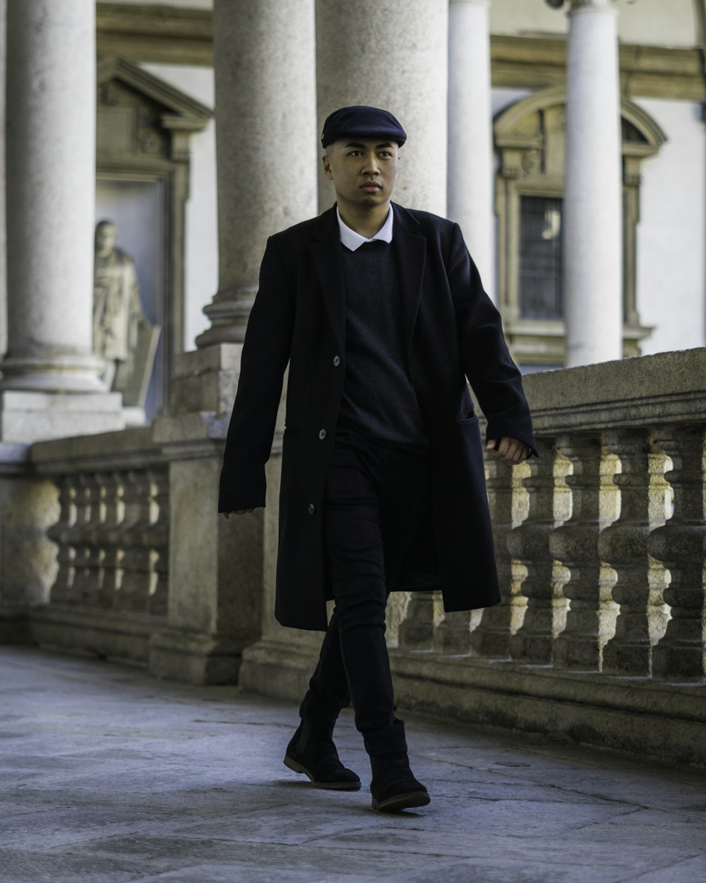 man in black coat walking on sidewalk during daytime