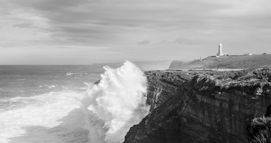 grayscale photo of ocean waves hitting rock formation in Santander Spain