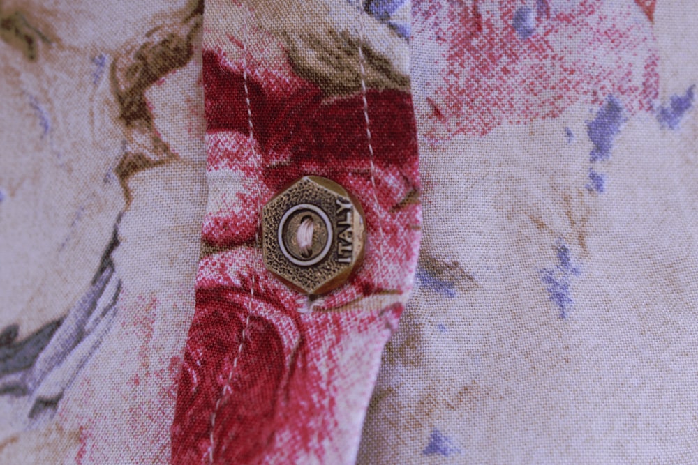 silver round coin on red and white textile