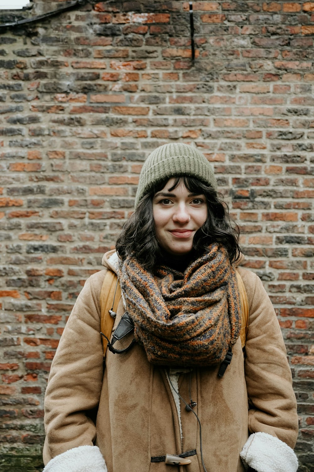 woman in brown coat wearing gray knit cap