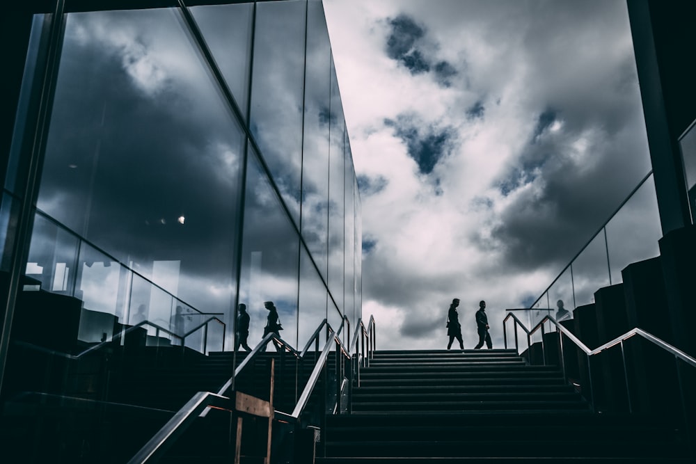 silhouette of people walking on stairs under cloudy sky