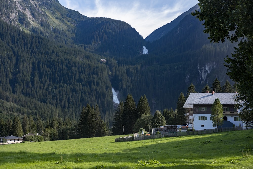 Casa bianca e marrone sul campo di erba verde vicino alla montagna durante il giorno