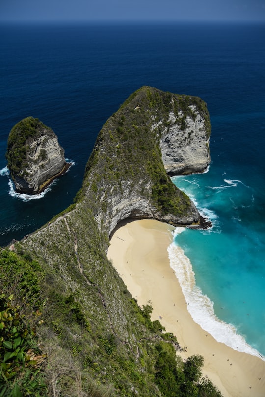 green and gray rock formation on seashore during daytime in Crystal Bay Nusa Penida Indonesia
