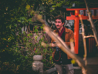 man in red polo shirt and black pants standing near green plant during daytime