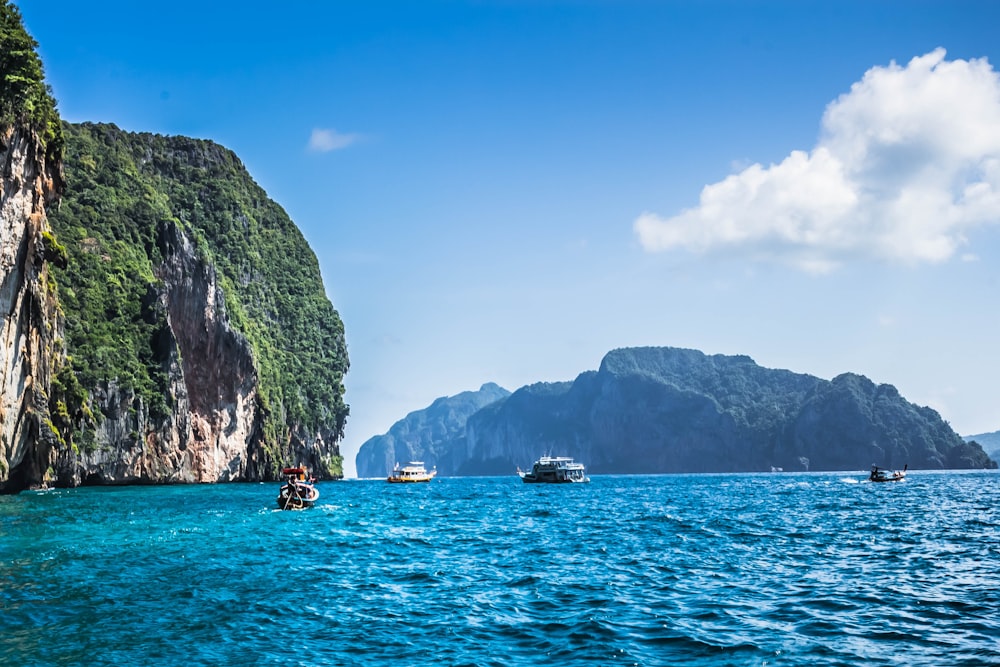 people riding boat on sea near mountain during daytime