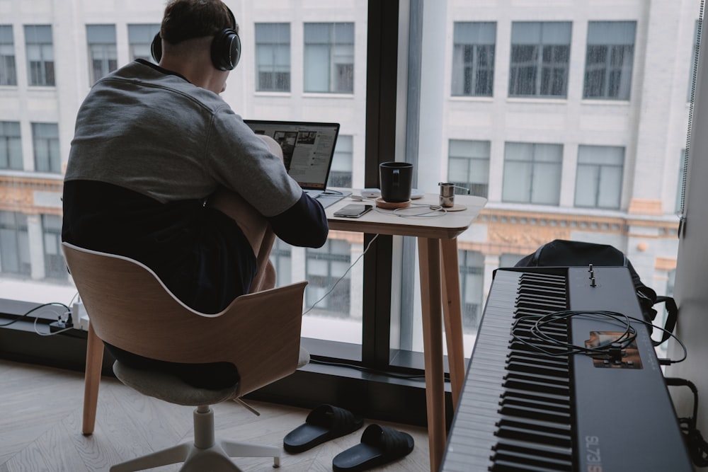 man in gray shirt sitting on chair in front of computer