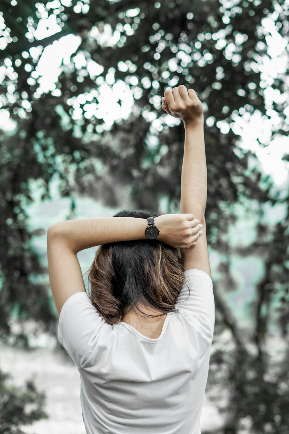 Mujer con camisa blanca de manga larga levantando las manos