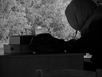 A candid photo of Laide Fujah seated at a desk, surrounded by books and notes, immersed in writing.