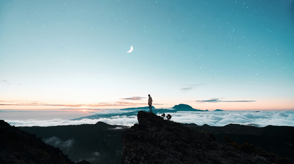 silhouette d’une personne debout sur une formation rocheuse pendant la nuit