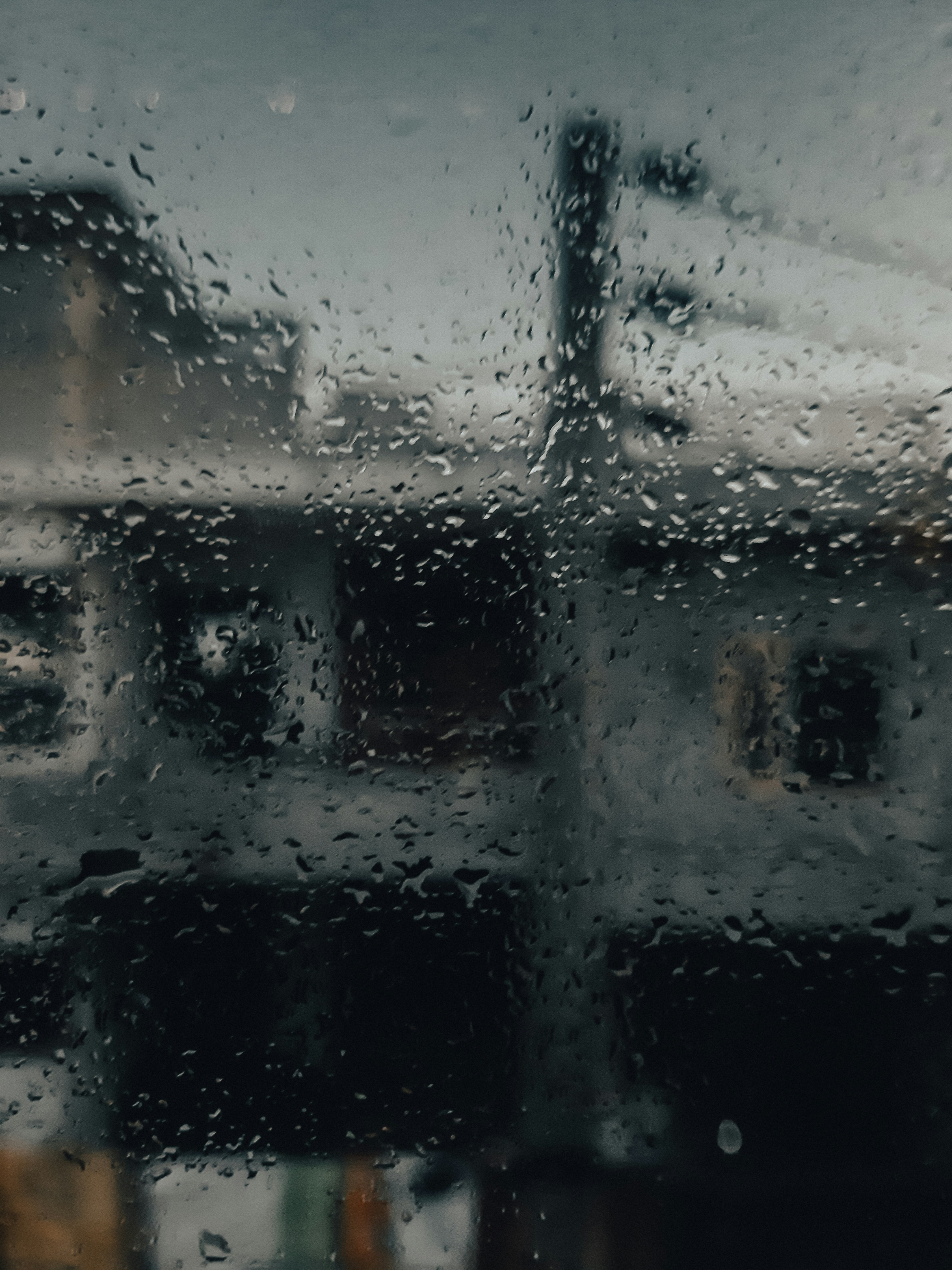 Rain drops on window glass, blurred city lights beyond, cool blue tones, solitary and contemplative