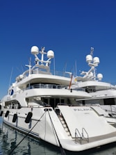 A luxury yacht docked at a pristine marina with technicians performing maintenance.