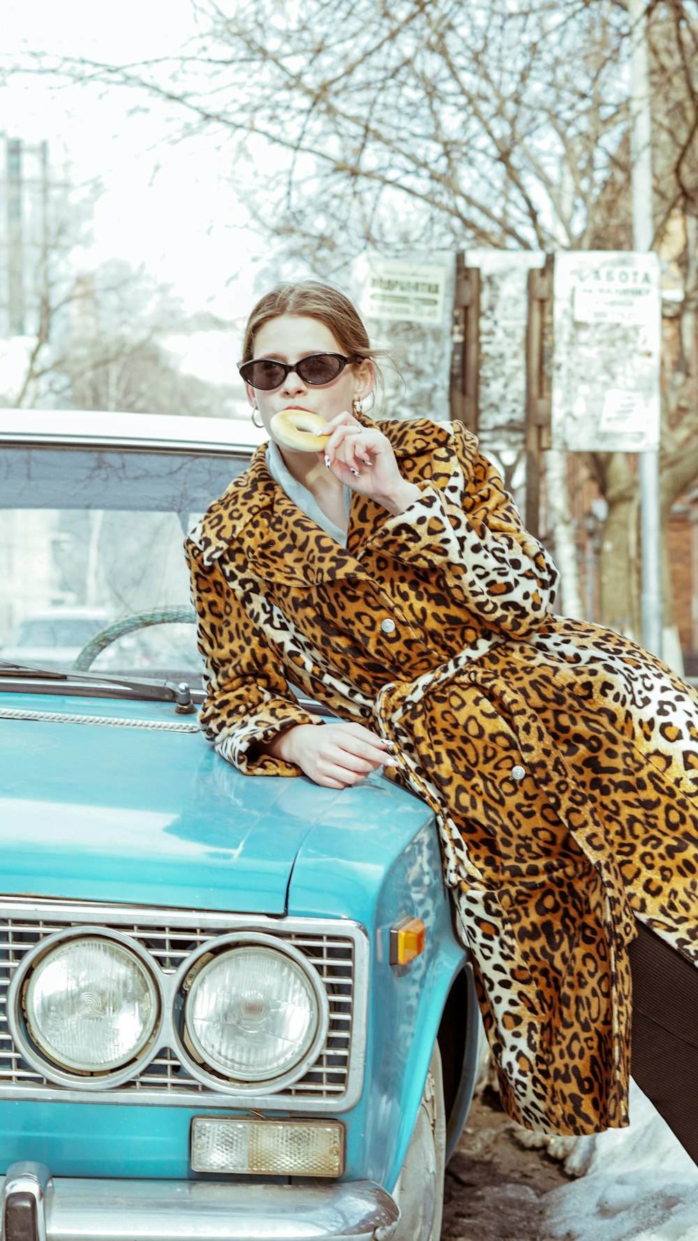 woman in brown and black leopard coat sitting on blue car