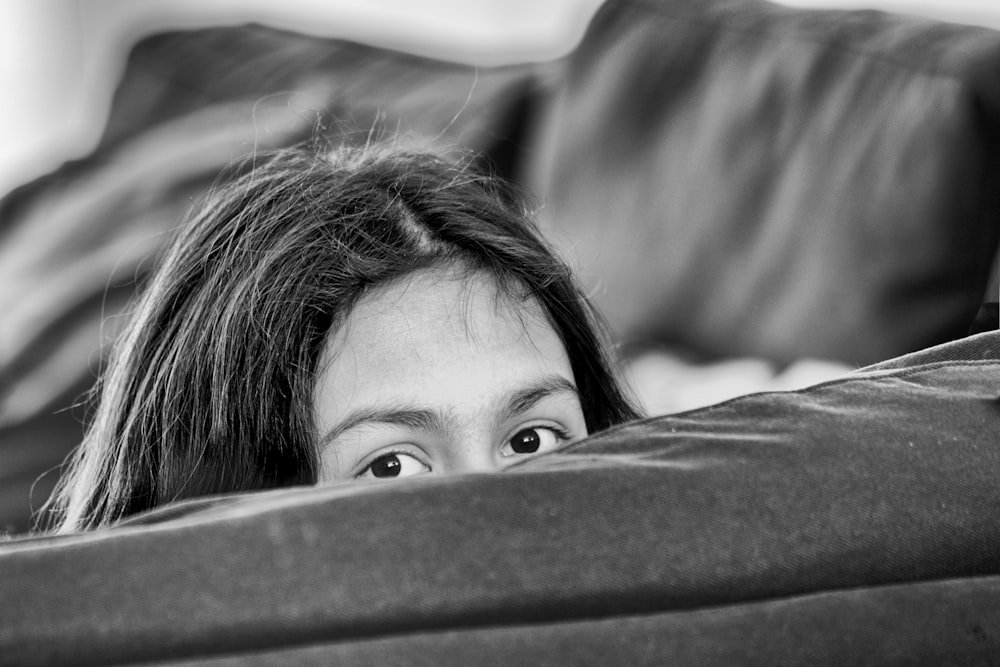 Foto en escala de grises de una niña acostada en la cama