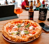 pizza with green leaf vegetable and sauce on brown wooden table