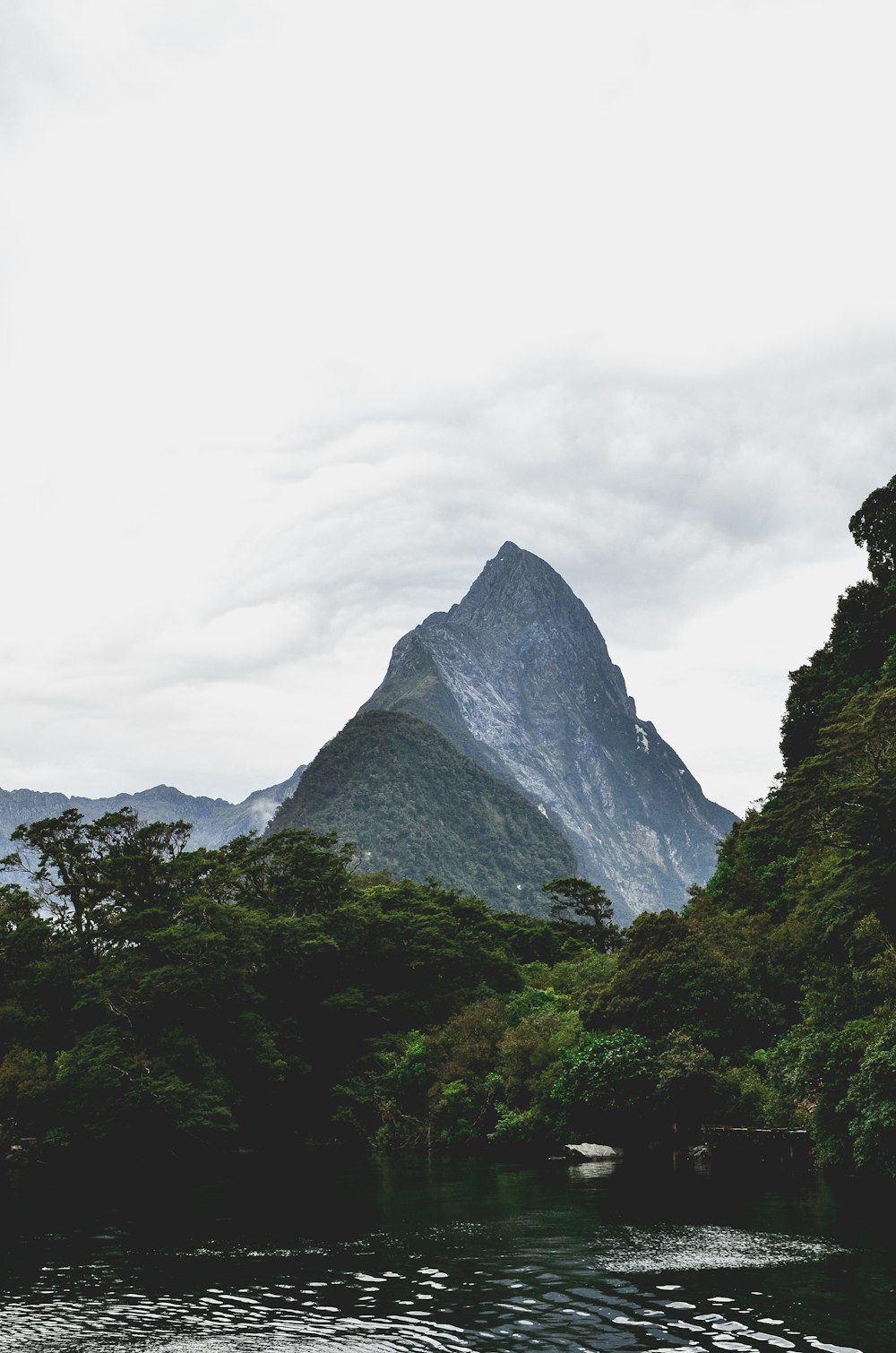 green trees near gray mountain under white clouds during daytime