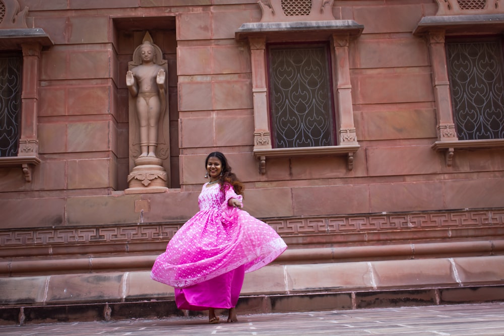 woman in pink dress standing on brown concrete stairs