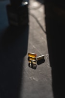 Three capsules lie on a dark surface, illuminated by a narrow beam of light, creating a strong contrast between light and shadow.
