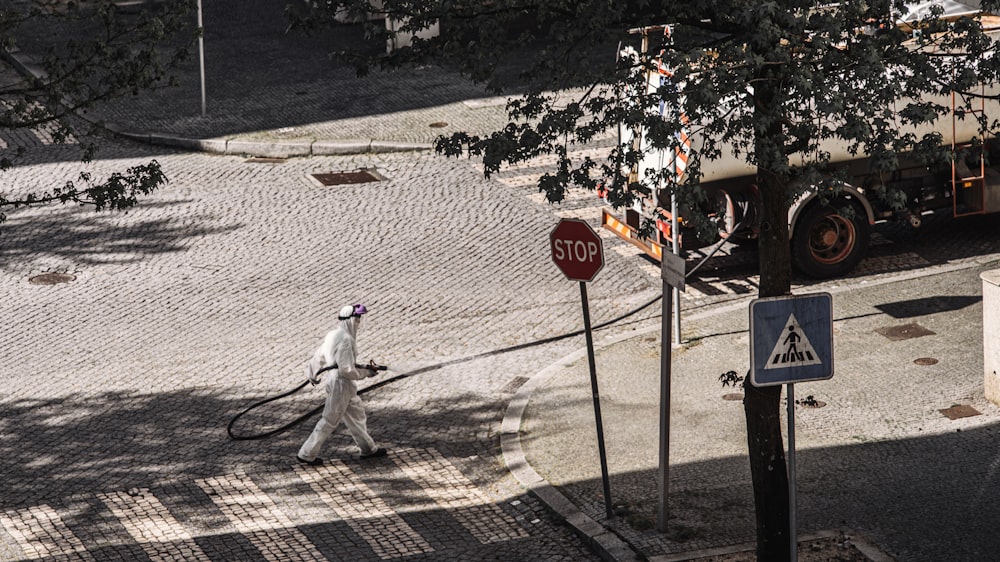 man in white long sleeve shirt and pants holding stop sign