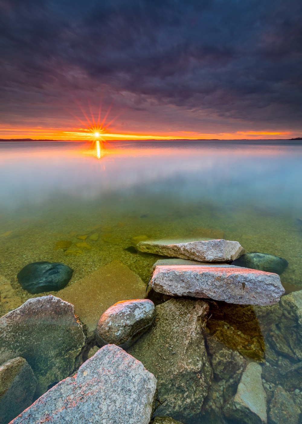 gray and brown rock formation near body of water during sunset