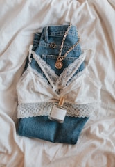 A pair of trendy jeans laid out on a flat surface with accessories.