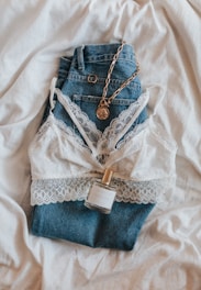 A casual-chic outfit featuring a stylish top and jeans laid out on a textured surface.