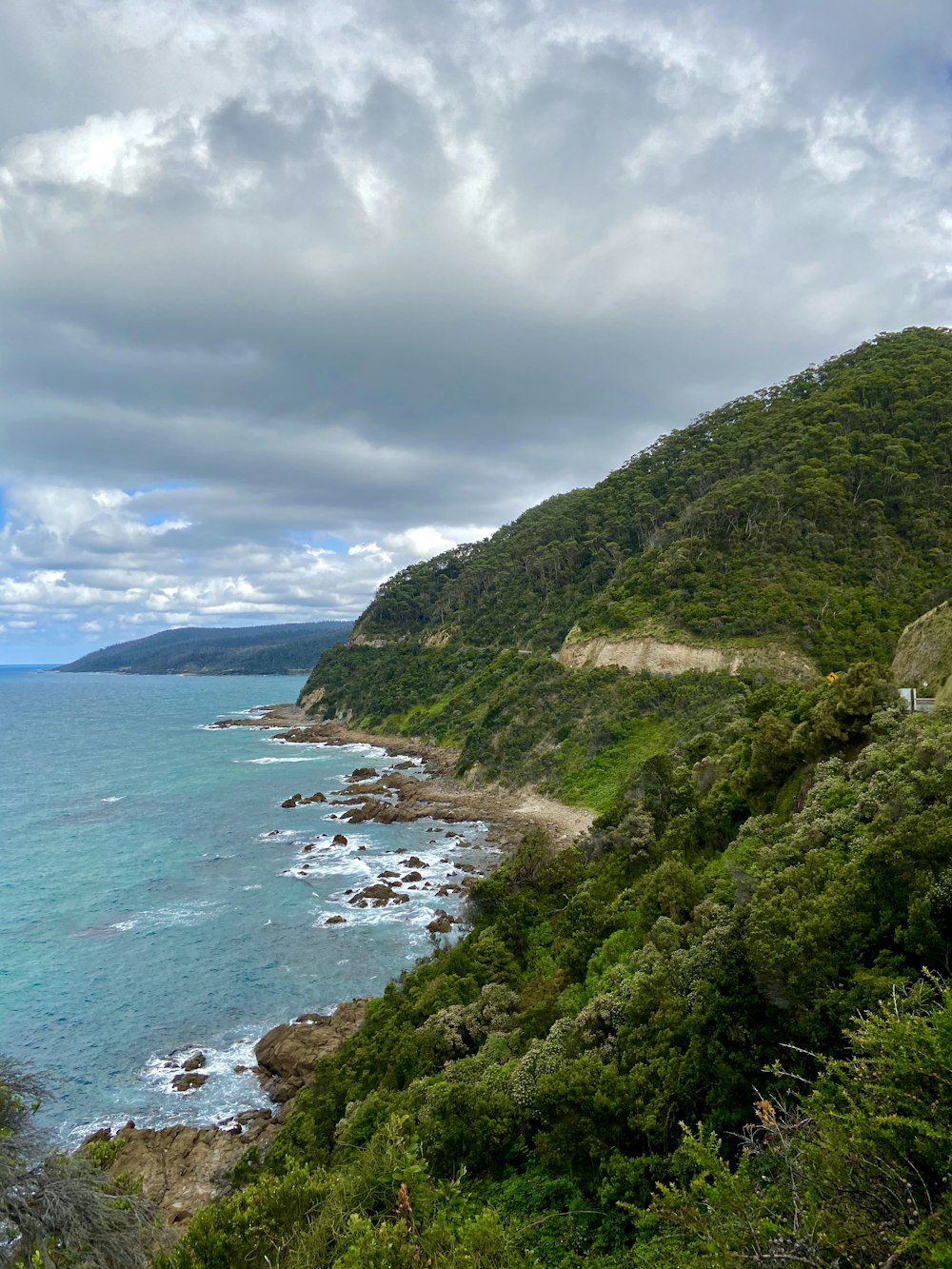 green mountain beside body of water under cloudy sky during daytime