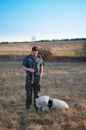 A friendly technician in uniform picking up dog waste in a sunny suburban yard.