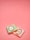 Two small wrapped chocolates lie on a pink surface. The wrapping includes elegant branding with the text 'Laduree Paris' and decorative golden embellishments. One wrapper is pastel green, and the other is a light pink.