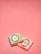 Two small wrapped chocolates lie on a pink surface. The wrapping includes elegant branding with the text 'Laduree Paris' and decorative golden embellishments. One wrapper is pastel green, and the other is a light pink.