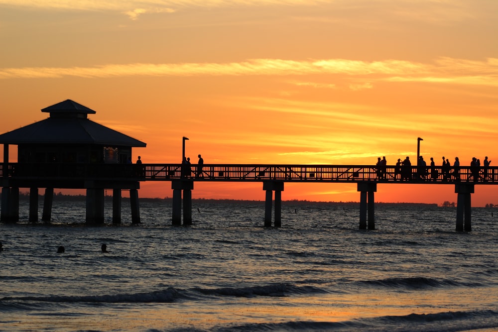 silhouette of dock on sea during sunset