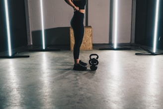 woman in black tank top and black leggings standing on white floor