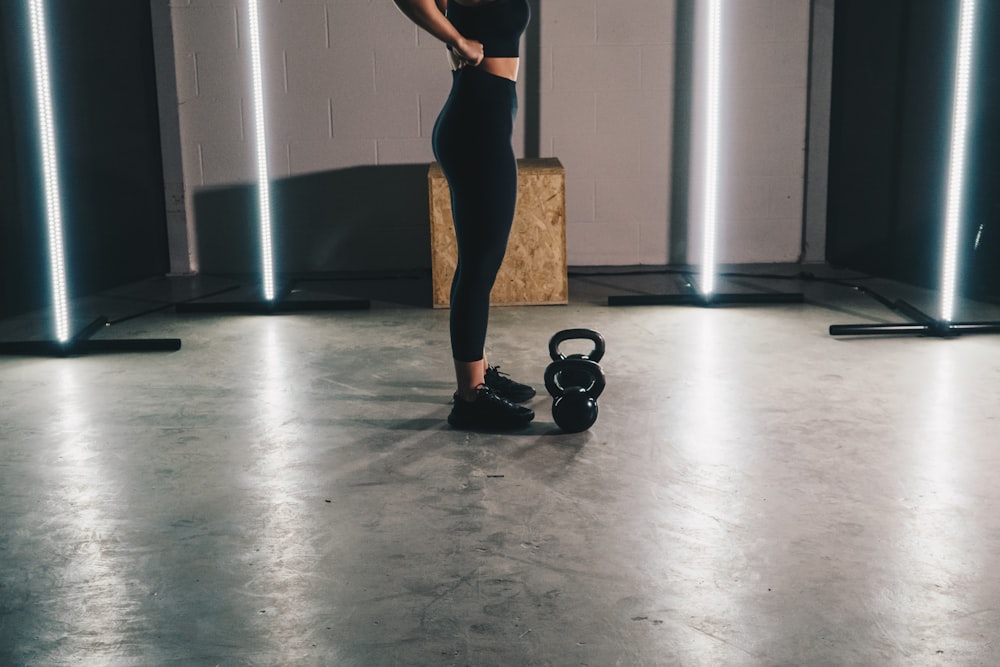 woman in black tank top and black leggings standing on white floor