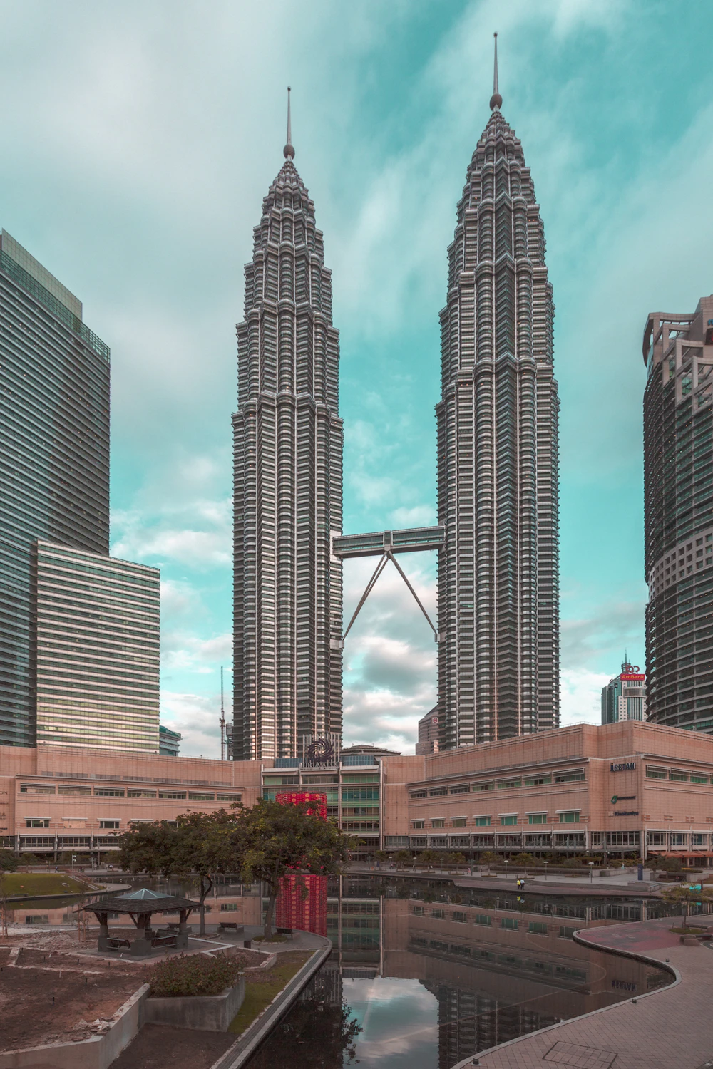 Petronas Twin Towers and skybridge reflected in the pool outside Suria KLCC on a clear blue day