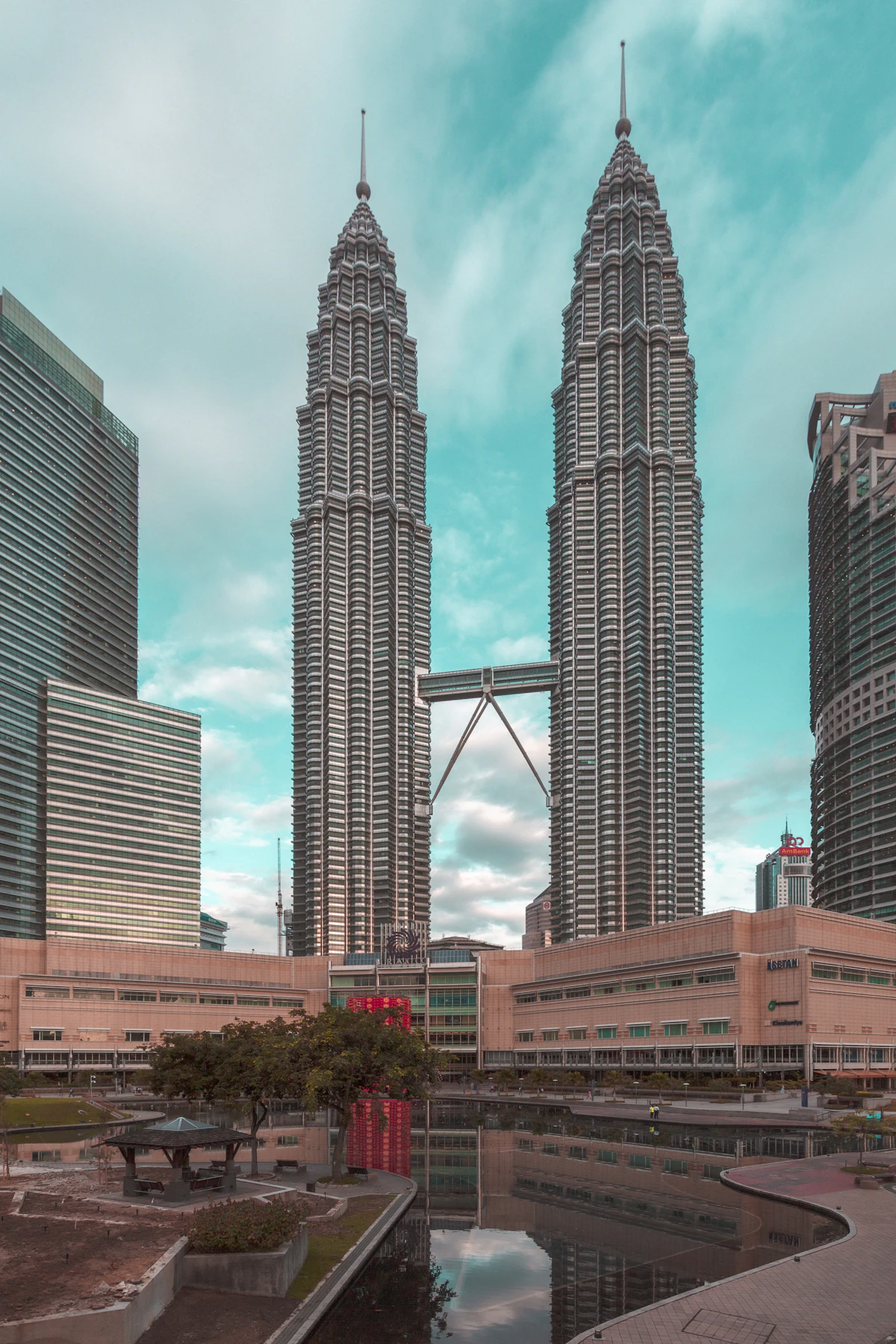 Petronas Twin Towers and skybridge reflected in the pool outside Suria KLCC on a clear blue day