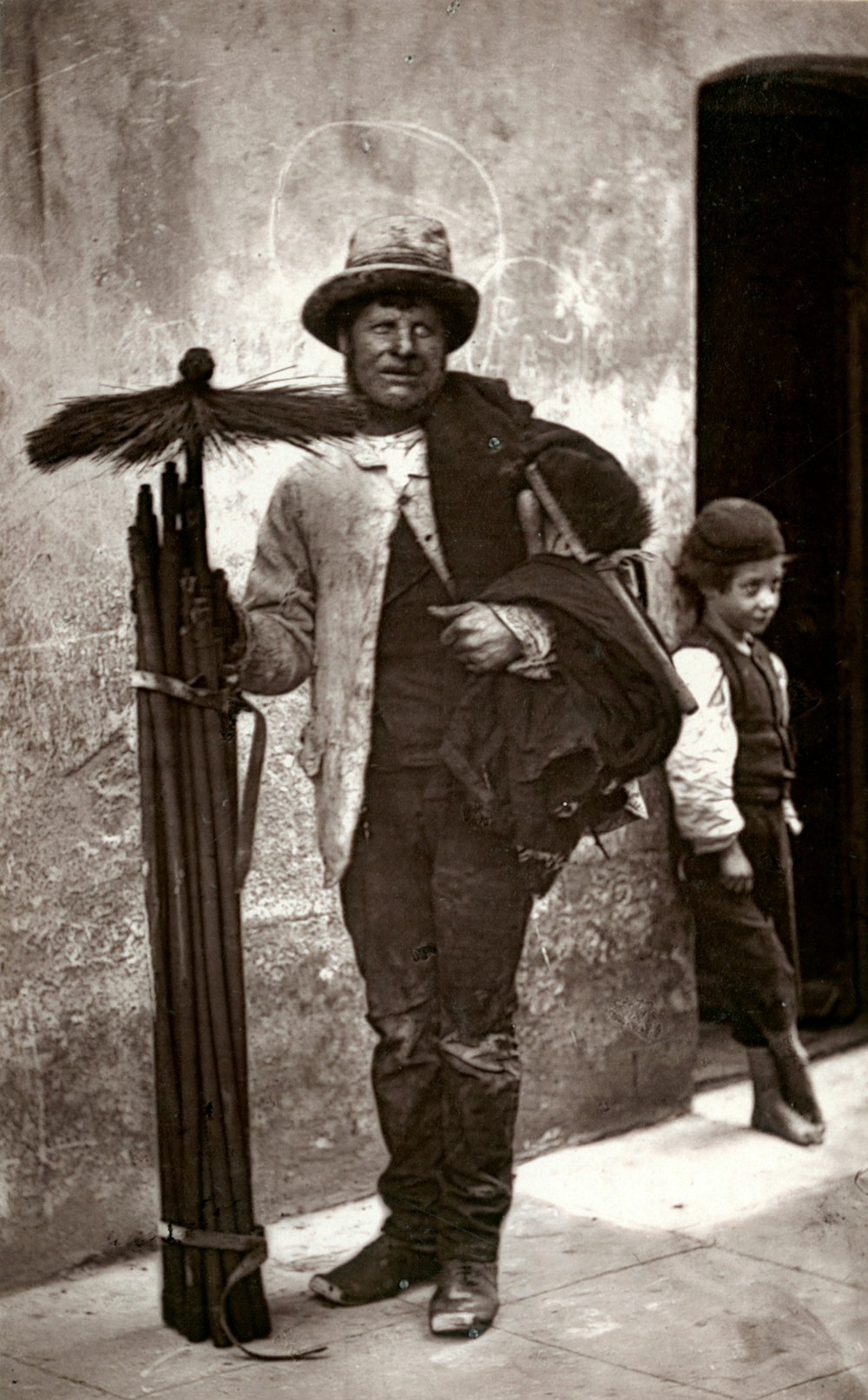 Foto en escala de grises de un hombre con abrigo negro sosteniendo un rifle de airsoft