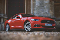 A sleek red sports car parked in front of the Amerimotors store.