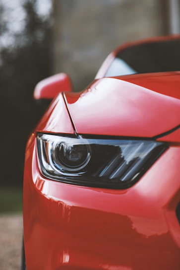 Close-up of a sleek sports car at a vibrant automotive event, with dynamic lighting highlighting its curves.