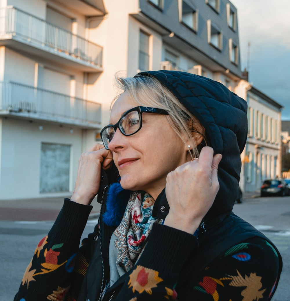 woman in blue and red floral jacket covering her face with blue and white scarf