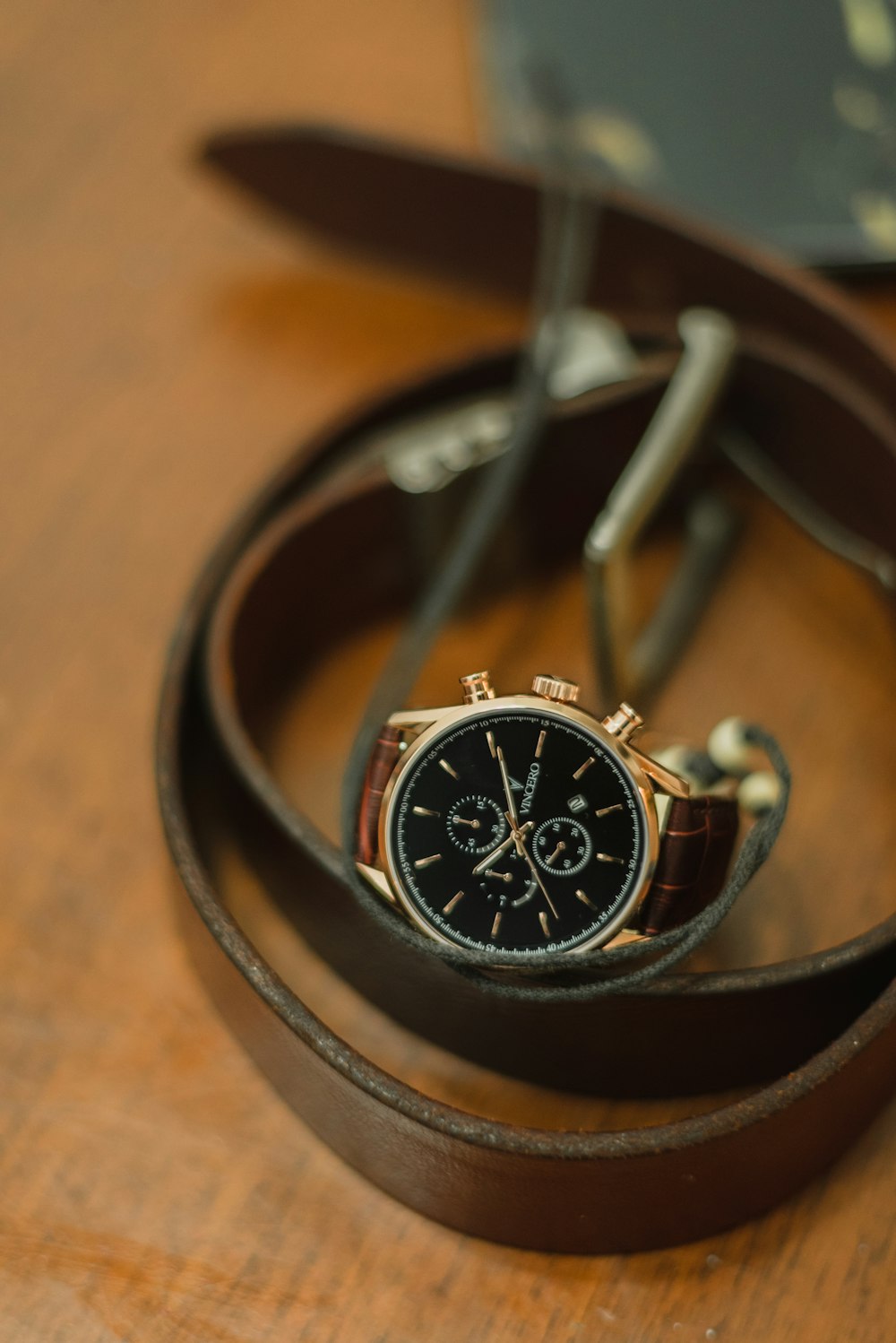 black and gold round analog watch with black leather strap