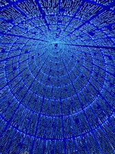 A mesmerizing pattern of blue lights forms a circular, tunnel-like structure against a dark background, creating an illusion of depth and infinite space.