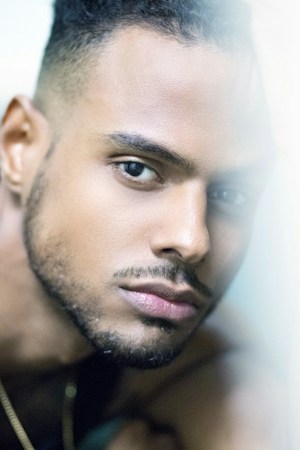A close-up portrait of a person focusing on their face. The image captures details like facial hair, skin texture, and eye color. The subject has a well-groomed beard and intense gaze, with a soft light falling on one side of the face.