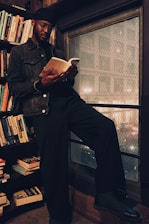A thoughtful man reading a book in a cozy library setting.