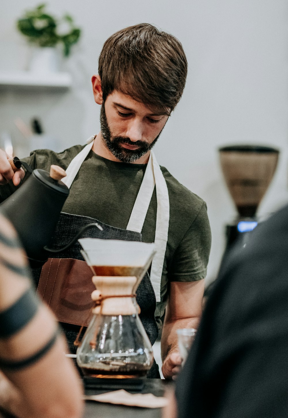 man in black apron holding black and white ceramic cup