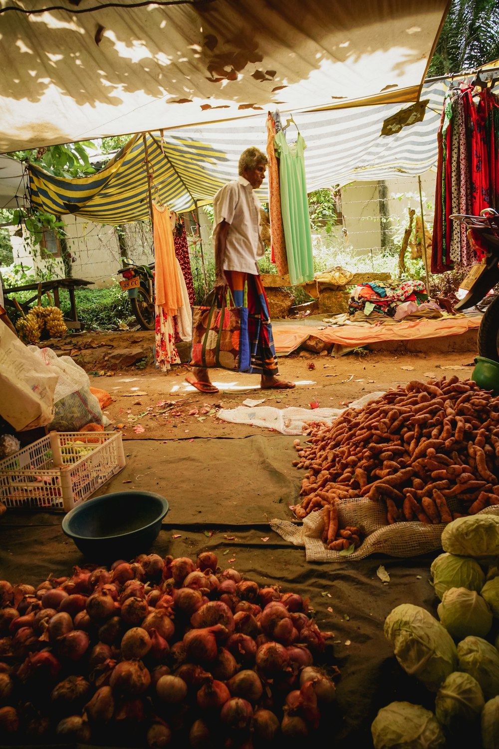 woman in white and blue dress standing near vegetable stall during daytime