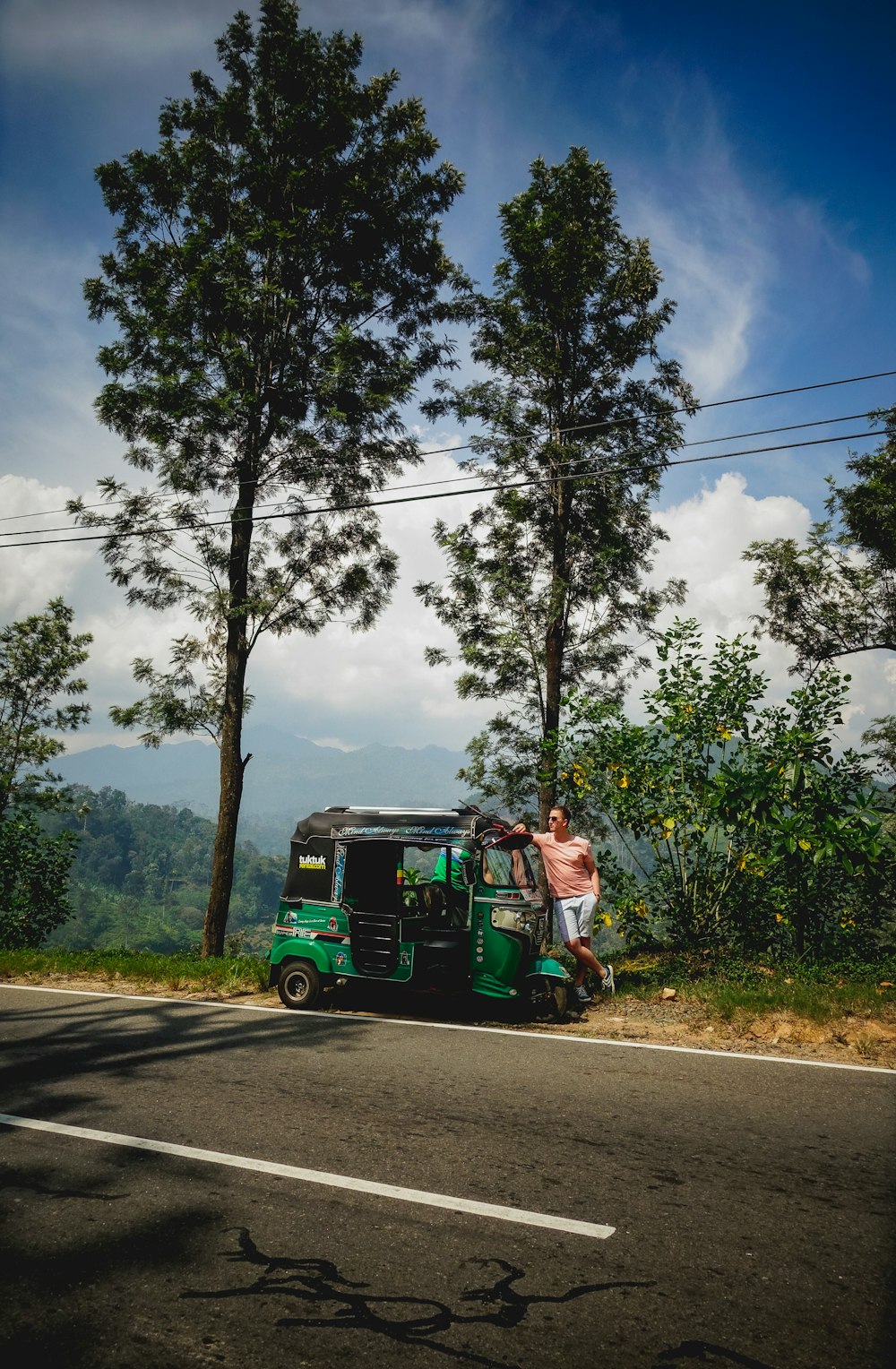 man in green jacket riding green and black auto rickshaw on road during daytime