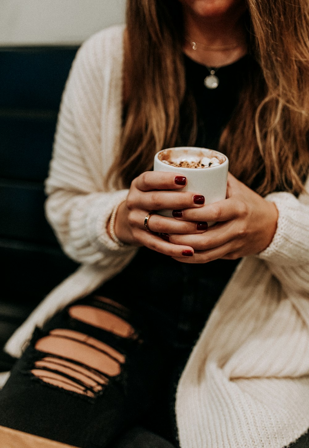 woman in white sweater holding white ceramic mug