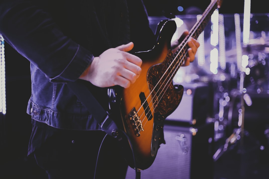 person in black coat playing brown electric guitar