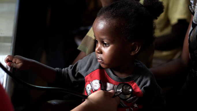 Professional observing a child attentively during a developmental activity in a bright, modern clinic setting.