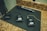 Several Sennheiser wireless microphone transmitters and receivers are laid out on a black mat on a countertop. There is also a handheld microphone positioned next to them. The devices appear to have display screens and numbered labels.